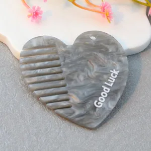 Detailed close-up of grey marble acrylic heart comb with hanging hole and letter print.
