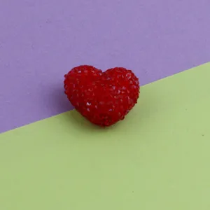 Close-up of red acrylic sugar heart bead, textured candy style surface for DIY craft.