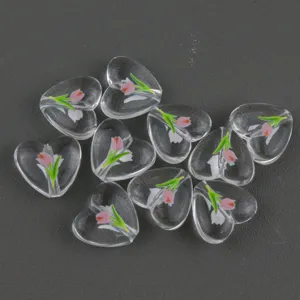 Close-up of clear acrylic heart beads with cute tulip print for handmade jewelry crafting.