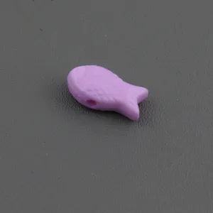 Gros plan d'une perle en forme de poisson violet clair, accessoire de bijouterie DIY.