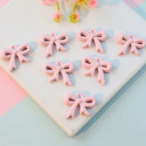 Pink acrylic bow pendants with holes, cute ribbon charms for DIY jewelry making and crafts.