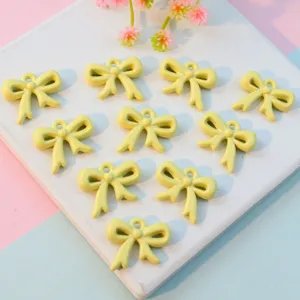 Yellow acrylic hollow bow knot pendant charm for jewelry making, DIY craft accessory detail view.