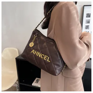 Detail view of brown quilted underarm bag with metal chain strap and stylish logo.