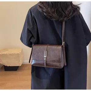 Vintage dark brown leather shoulder bag detail, stylish clasp design for women outfit.