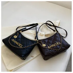 Detailed close-up view of quilted black and brown shoulder bag featuring metal chain and logo.