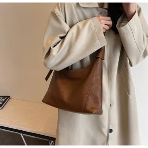 Detailed view of stylish brown lychee grain leather shoulder bag with chic knot strap design.