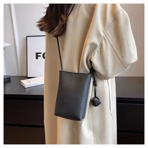 Minimalist black mini crossbody phone bag detail view, premium leather texture, chic knot charm.