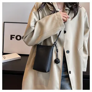 Detail view of a minimalist black leather mini crossbody phone bag featuring a chic knot strap.