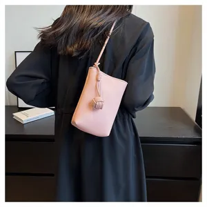Close-up detail of a minimalist pink leather mini crossbody phone bag with knot accent.