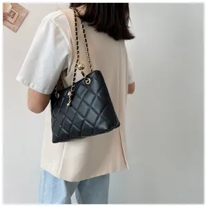 Detail shot of black quilted shoulder bag featuring gold chain strap and metal ball charm.