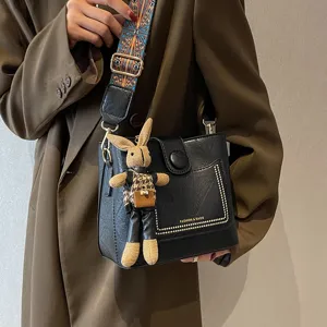 Elegante borsa a secchiello nera da donna con ampia tracolla etnica e grazioso ciondolo coniglio.