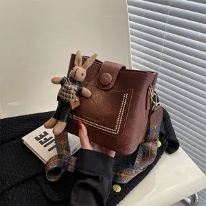 Borsa a secchiello marrone vintage da donna con tracolla larga e grazioso ciondolo con coniglio.