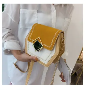 Close-up detail of stylish color-block crossbody bag with chain strap and unique geometric clasp.