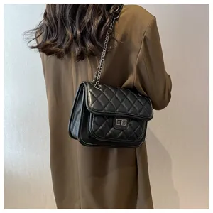 Close-up view of the black quilted shoulder bag with chain strap and metal lock in daily use.