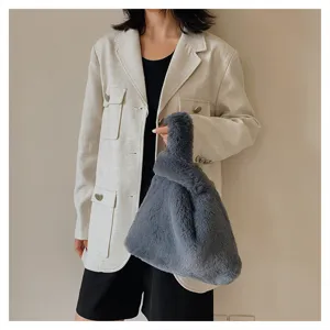 Detailed view of trendy fuzzy faux fur knot handbag, soft plush texture, stylish grey blue.