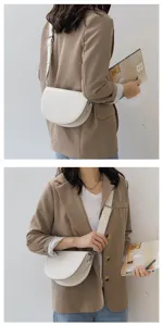 Minimalist white saddle shoulder bag detail view, featuring wide strap and smooth leather texture.