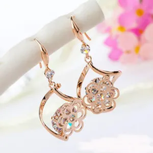 Detailed view of rose gold drop earrings with sparkling zirconia and floral geometric design.