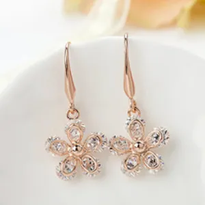 Close-up detail of rose gold flower drop earrings with sparkling clear cubic zirconia stones.