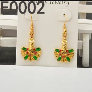 Close-up detail of Christmas candle and holly leaf drop earrings, alloy with red and green rhinestones.