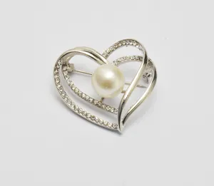 Close-up detail of the double heart rhinestone and pearl brooch, elegant accessory design.