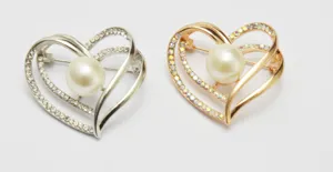 Detailed view of elegant heart-shaped pearl rhinestone brooches in silver and gold tones.