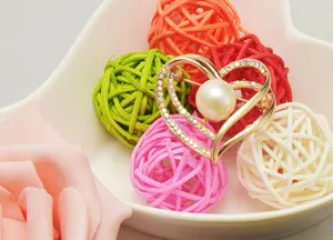 Detail view of the elegant heart-shaped pearl rhinestone brooch displayed with colorful rattan.