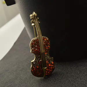 Vintage gold-toned violin brooch pin featuring sparkling red rhinestones for elegant fashion style.