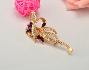 Exquisite gold-tone leaf brooch featuring sparkling clear rhinestones and elegant purple gems.