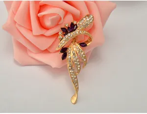 Elegant crystal brooch detail shot featuring purple gems and gold tone floral design.