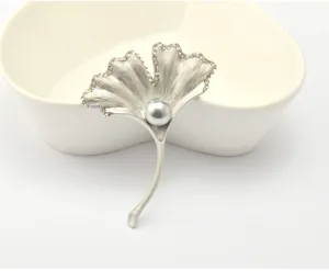 Ginkgo leaf brooch detail shot, silver metal with rhinestones and central pearl decor.