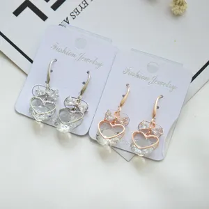 Charming heart-shaped zircon dangle earrings with bow detail, elegant jewelry detail shot.