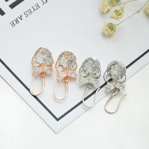 Close-up detail shot of exquisite heart-shaped zircon earrings with bow charms in dual-tone finish.