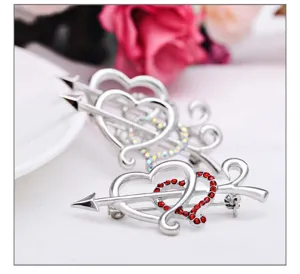 Close-up shot of the exquisite double heart arrow brooch, showcasing sparkling red crystal details.