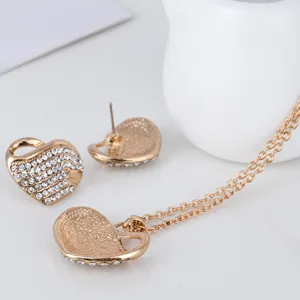 Vue detaillee de l'ensemble de bijoux collier et boucles d'oreilles coeur en strass or.