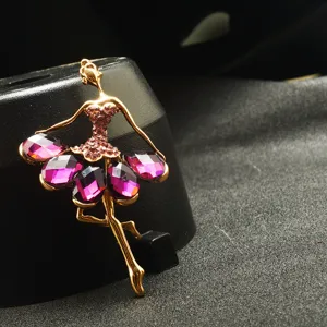 Nahaufnahme einer stilvollen goldfarbenen Ballerina-Brosche mit funkelnden lila Strasssteinen.