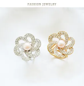 Close-up detail of rhinestone pearl flower scarf buckle, elegant metallic shawl ring decoration.