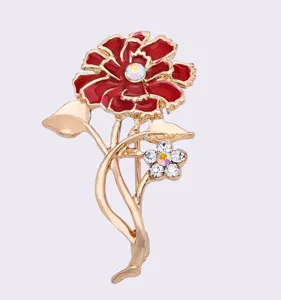 Vista detallada de broche flor roja de cristal, tallo dorado y pedrería brillante.