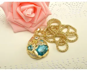 Gros plan détaillé du collier pendentif en cristal bleu plaqué or avec un motif de feuilles.