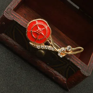 Primer plano detallado de un broche de clavel esmalte rojo con pedrería en caja de madera.