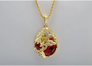 Gros plan détaillé du collier pendentif goutte en cristal plaqué or avec motif de blé et de rose.