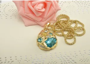 Vue détaillée du collier pendentif larme en cristal bleu plaqué or avec design de feuilles.