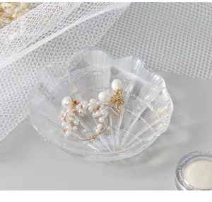 Detailed close-up view of iridescent glass shell jewelry dish and delicate pearls on display table.