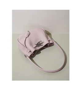 Detailed shot of light pink leather bucket bag featuring metal lock closure and shoulder strap.