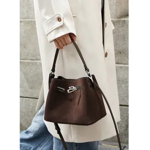 Detail view of a retro brown suede bucket bag featuring metal turn-lock closure.