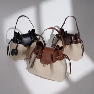 Vista detallada de bolsos tipo cubo de lona minimalista con ribete de piel y cierre metálico.