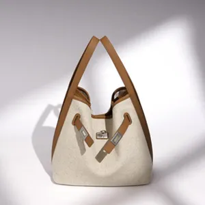 Vista detallada del bolso tote minimalista de lona y cuero con cierre de cerradura metálica.