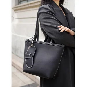 Vista detallada de un elegante bolso tote de hombro negro de cuero con costuras blancas.
