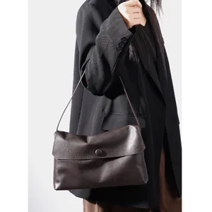 Minimalist dark brown leather shoulder bag featuring sleek flap and delicate slim strap.