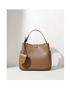 Detail view of the brown leather bucket bag showcasing its fine texture and chic side pouch accessory.