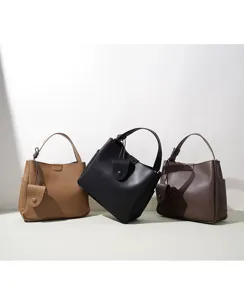 Detailed view of three minimalist leather bucket bags in camel, black, and brown with knot handle.